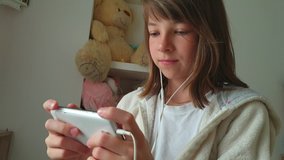 teenage girl with phone in hand and headphones, children and modern technology.