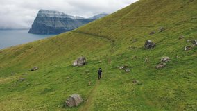 Hiker with a backpack walks on the island of Kalsoy in Faroe Islands. 4K UHD video.