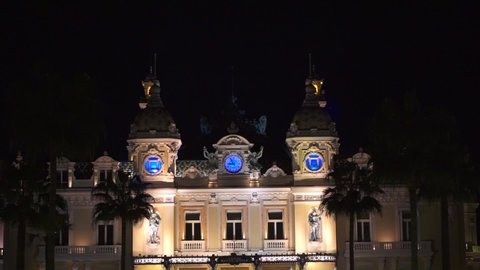 Monaco, Monte-Carlo August 1, 2019: cinematic view of the domes and clocks, surrounded by statues of the casino of Monaco at night. Architecture in Monaco. Blue light 9:00 in Monaco.