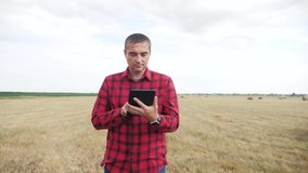 smart farming agriculture concept. man farmer studying a haystack in a field on digital tablet. slow motion video. lifestyle male agronomist botanist farmer working in the field