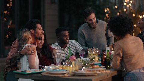 young group of friends celebrating at dinner party chatting sharing healthy food sitting at table enjoying weekend reunion relaxing on beautiful summer evening outdoors 4k