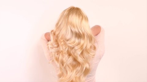 Beautiful long blond Hair. Beauty woman with luxurious curly white hair. Sexy blonde Model girl with Healthy Hair. Lady with long hairstyle. Cure, extensions. Over white background. 4K slow motion