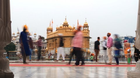 AMRITSAR, INDIA - MARCH 18, 2019: a time lapse of sikh worshipers walking past the golden temple in amritsar, india