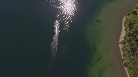 Rotating aerial of a motorboat with a long wake and reflected sunball