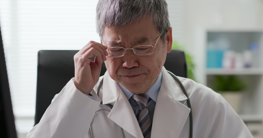 Senior asia doctor feel tired and has headache