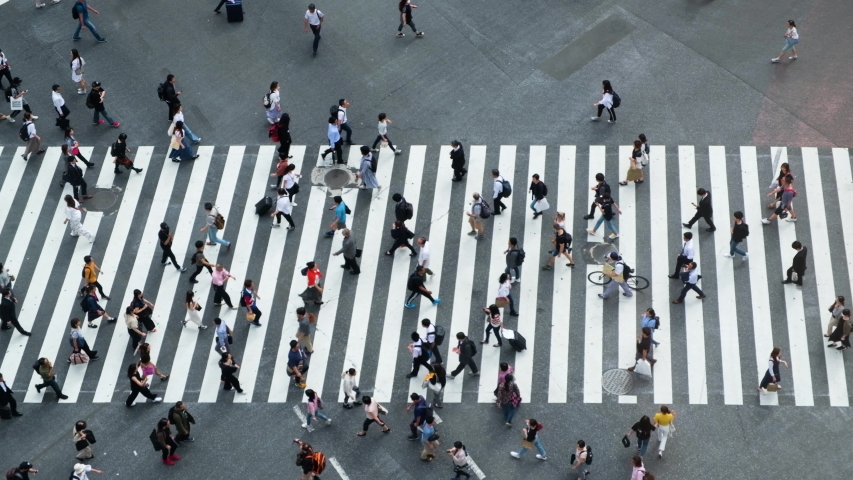 Aerial view of pedestrians walk at Shibuya Crossing. The scramble crosswalk is one of the largest in the world. Shibuya, Tokyo, Japan. | Shutterstock HD Video #1034411039