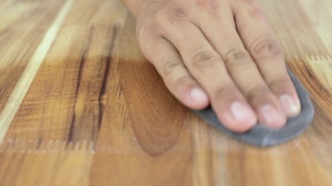 Man cleaning and polishing a wooden surface And applying wood maintenance products.
