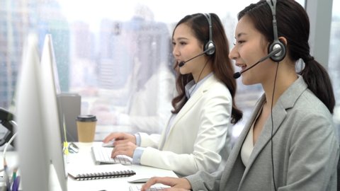 Asian customer service operator team talking on headsets and using computer at the call center office in the city
