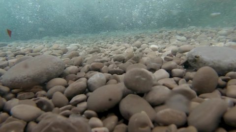 SLOWMO Underwater view of a tidal waveing pebbles on sea floor