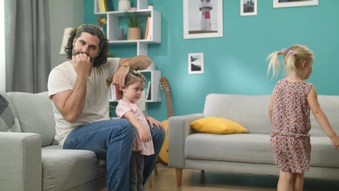 Young bearded father brushing the hair of his little girl and makes the tail
