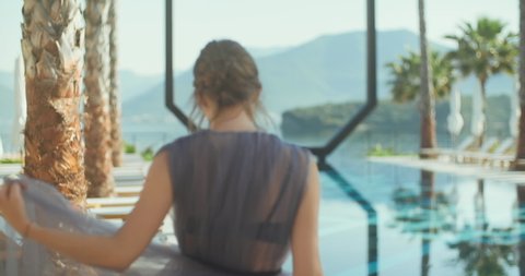  Young lady walking over the pool on holidays. Travel vacation woman relaxing enjoying Montenegro looking at Amazing view of sea.  European tourist destination. 
