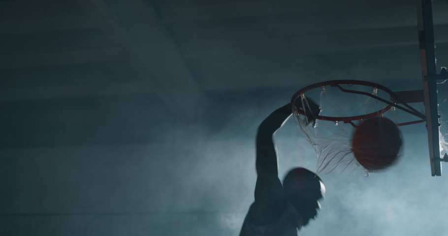 Cinematic slow motion shot of an young african professional male player is making a  slam dunk during a basketball work out in a gym. Royalty-Free Stock Footage #1034419625