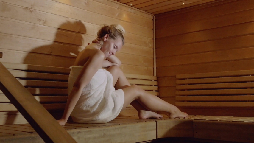 Mature woman wearing towel sitting in a sauna stock photo