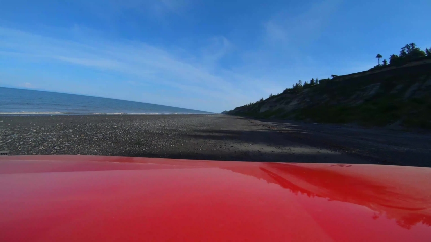 Double time POV over the hood of a red off road vehicle while driving along a desolate beach near Anchor Point, Alaska