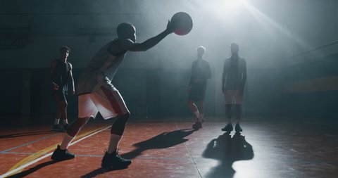 Cinematic slow motion close up shot of young professional male players are practicing a basketball work out in a gym.