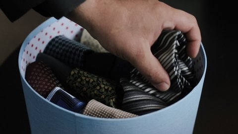 Paper Box With Classic Ties For A Holiday Or Business Meeting. Close-up Of Person Chooses And Holds A Tie In His Hand.