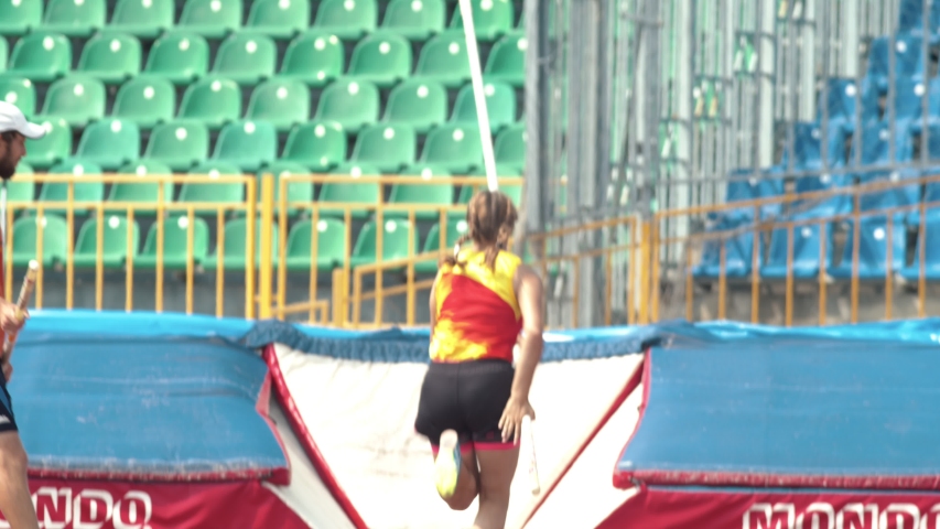 Pole vault - a young woman jumps over the bar in the stadium