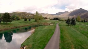 
rise pan over water trap and course. Clip shows an aerial view of water trap and golf course. The video shows the mountains, grassy field and trees as well.