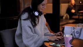 Young millennial woman wearing electronic headphones for watching online tutorial webinar in public place using 4g wireless on touch pad, Caucasian female chatting via digital tablet