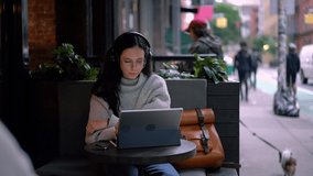 Beautiful millennial digital nomad working remotely on modern touch pad with portable keyboard using public internet connection in sidewalk cafe terrace, Caucasian woman reading content text