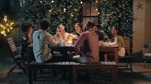 dinner party friends celebrating evening together sharing homemade meal enjoying casual conversation having fun weekend reunion relaxing on calm summer night outdoors 4k footage