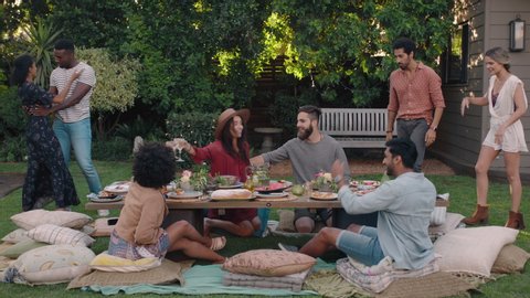 happy friends arriving at garden party celebration hugging enjoying friendship reunion gathering sitting at table with healthy food sharing weekend picnic together 4k Video stock