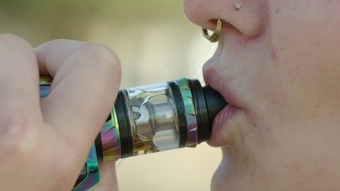Closeup of a Caucasian woman taking a drag from a vape, 60 fps