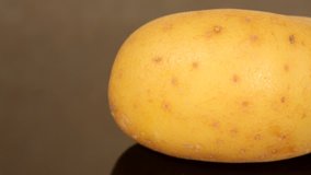 Closeup of a ripe yellow potato on a black pan background from a sliding dolly