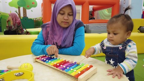 ALOR SETAR, MALAYSIA - CIRCA JUNE, 2019: 4k footage Muslim mother and daughter spending quality time together playing xylophone at indoor playground area.