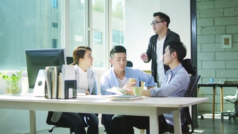 four young asian businessmen and woman meeting in office discussing business in office of small company