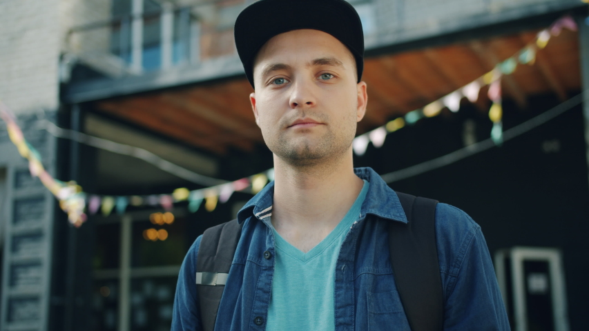 Portrait of good-looking young man standing outdoors in the street looking at camera with serious face. People, modern city and urban lifestyle concept. Royalty-Free Stock Footage #1034469038