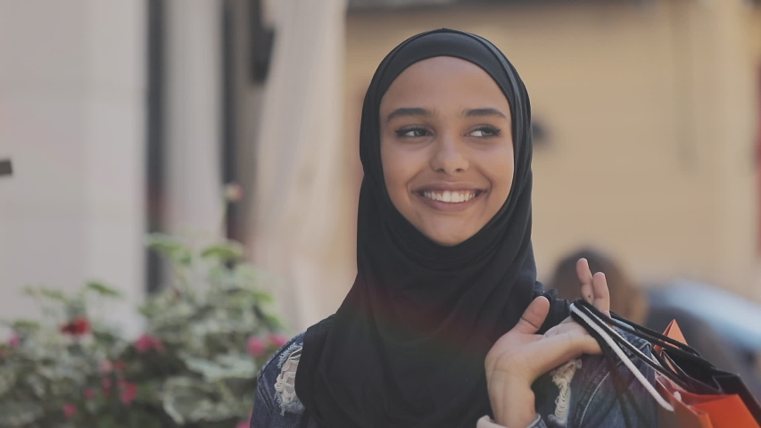 Happy young muslim woman in hijab walking down the street with shopping bags in her hand. Royalty-Free Stock Footage #1034472536