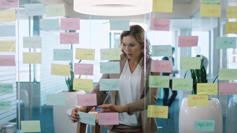 beautiful business woman using sticky notes brainstorming ideas planning strategy problem solving with creative mind map working on solution in office 4k