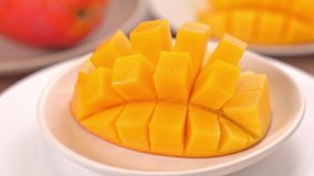 Beautiful fresh chopped mango, showing on a rotating white plate, close up, 4K video shot.