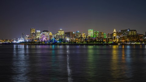 Night time lapse of Montreal old port with the Saint Lawrence river and a ferris wheel, Zoom in shot from Saint Helen's Island