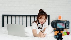 4K Locked shot pretty woman lying on bed and listening sound from headphone with tablet and confirm OK, she recording clip to present new product to social network, blogger concept
