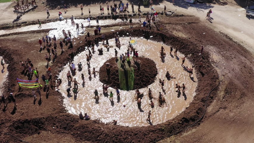 Aerial footage of a large crowd of people at a Mud festival.