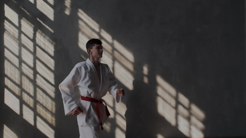 Slow motion. A young athlete in excellent physical condition shows kicks. He raises his legs high. Traditional martial arts of Korea. Tactical strategy battle. Taekwondo or karate.