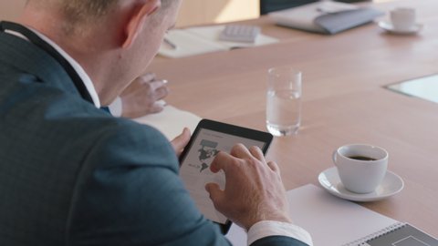 businessman using tablet computer in office meeting corporate executive browsing financial data for company marketing project on mobile device