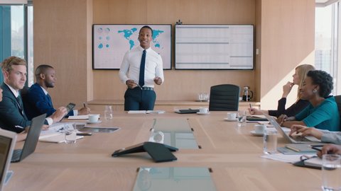 Black businessman presenting financial data on tv screen sharing project with shareholders team leader briefing colleagues discussing company growth ideas in office boardroom presentation