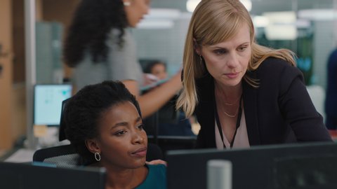 business woman meeting with colleague using computer team leader pointing at screen helping coworker discussing strategy in corporate workplace