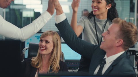 sales team celebrating success with high five looking at financial graph data on computer screen happy business people enjoying corporate victory achievement in office