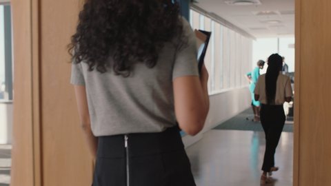 attractive business woman walking through busy office holding tablet computer enjoying successful leadership career in corporate workplace
