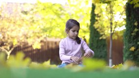 Girl on the outdoor is playing and rejoices with autumn leaves. 4K video.