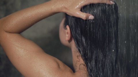Brunette woman washing hair in the shower. Closeup. View from back.