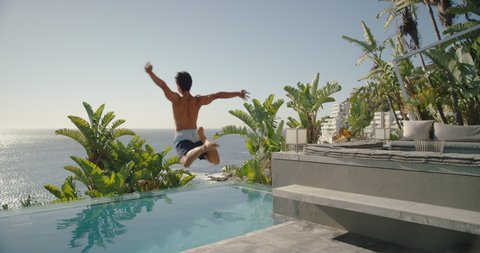happy man running jumping in swimming pool at luxury hotel with beautiful ocean view having fun summer vacation enjoying swim at tropical resort on warm sunny day mediterranean travel 4k