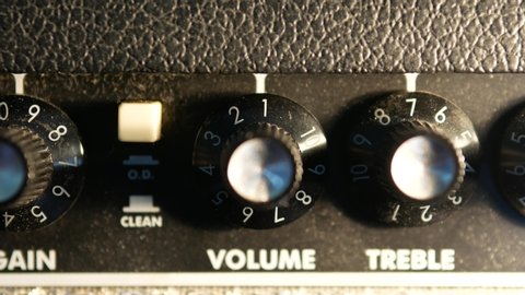 Men hand turning the volume knob on guitar amplifier