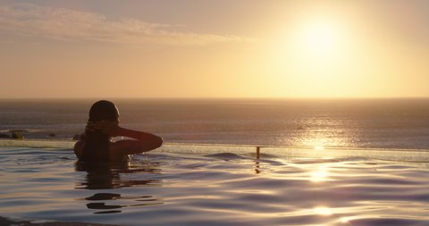 woman relaxing in swimming pool at luxury hotel spa enjoying beautiful sunset view of ocean mediterranean travel holiday resort 4k