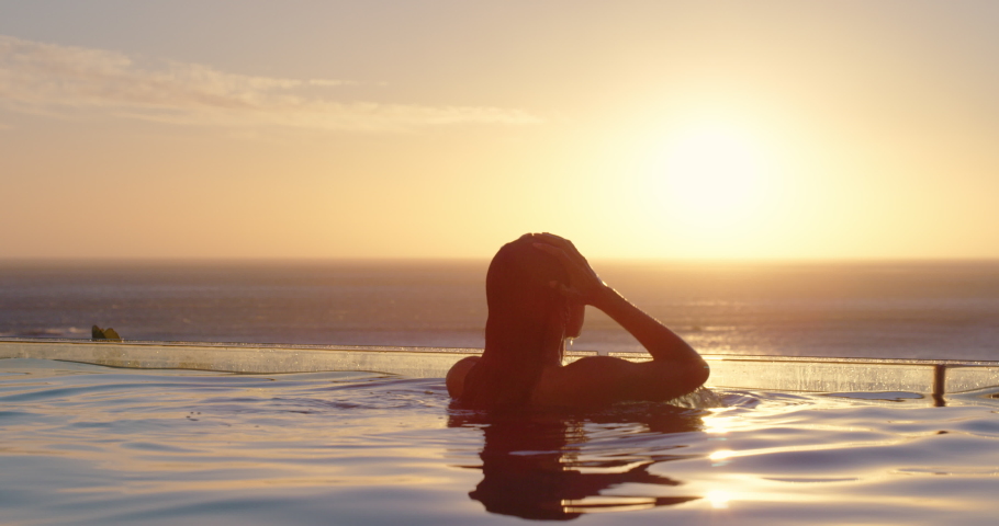 Woman relaxing in swimming pool at luxury hotel spa enjoying beautiful sunset view of ocean mediterranean travel holiday resort 4k | Shutterstock HD Video #1034496932