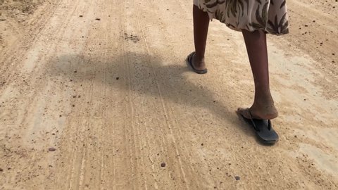 Poor child feet walking on a dirt road on a hot sunny day.